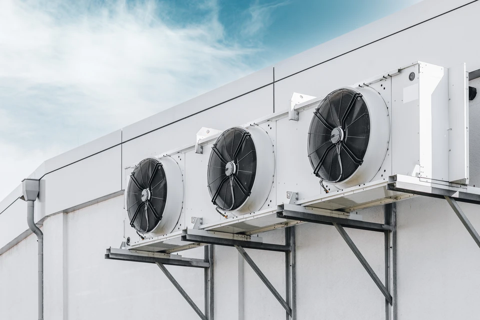 Intérieur industriel avec technicien en uniforme bleu effectuant contrôle d'extincteurs rouges